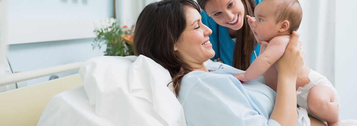 A mother holding up her baby post partum with nurse, happy!