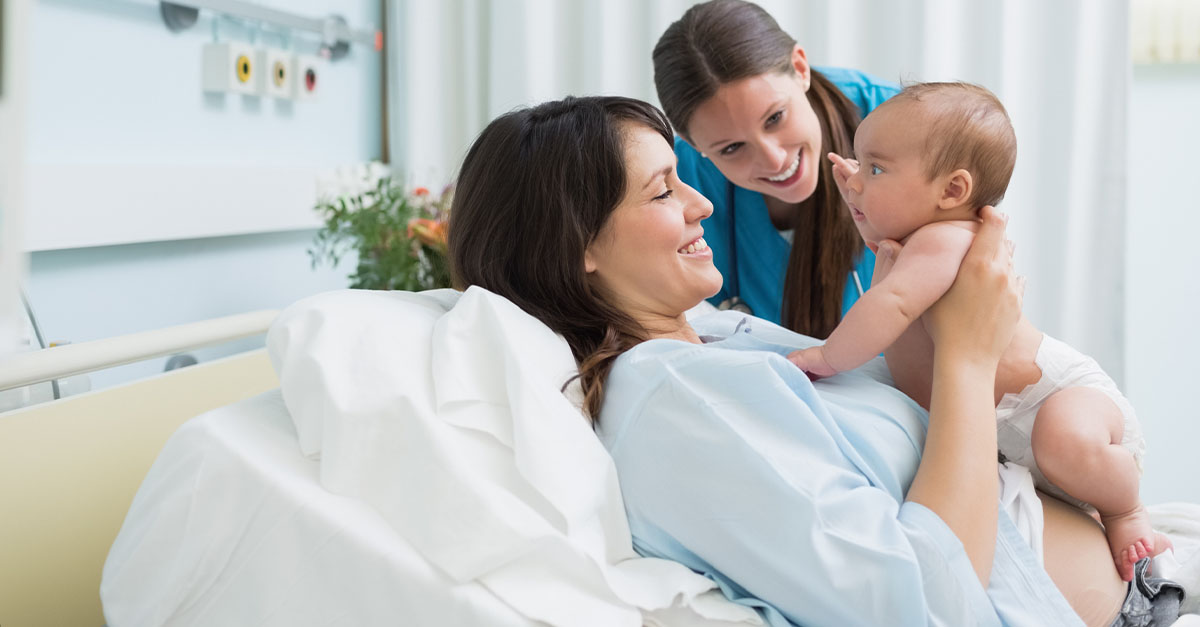 A mother holding up her baby post partum with nurse, happy!