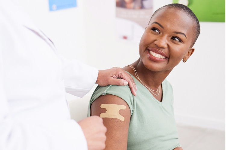 An African American lady receiving a vaccination from her doctor.