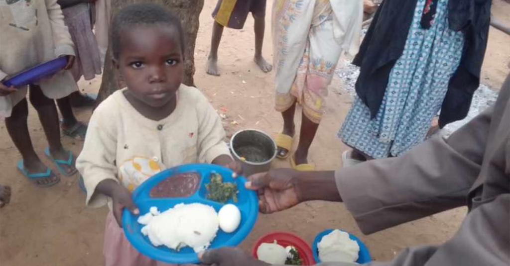 A hungry child holding a plate of food.